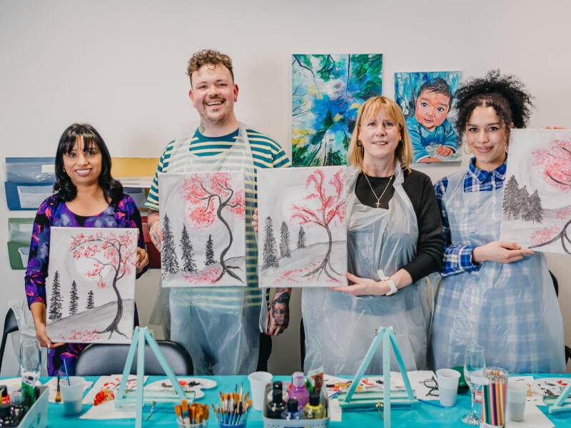 group of people posing with artworks at wine and paint